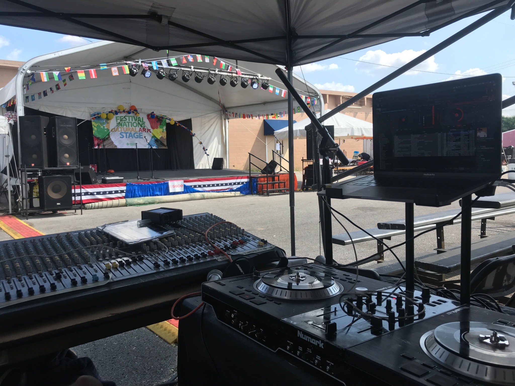 DJ controller and mixer position facing an outdoor stage