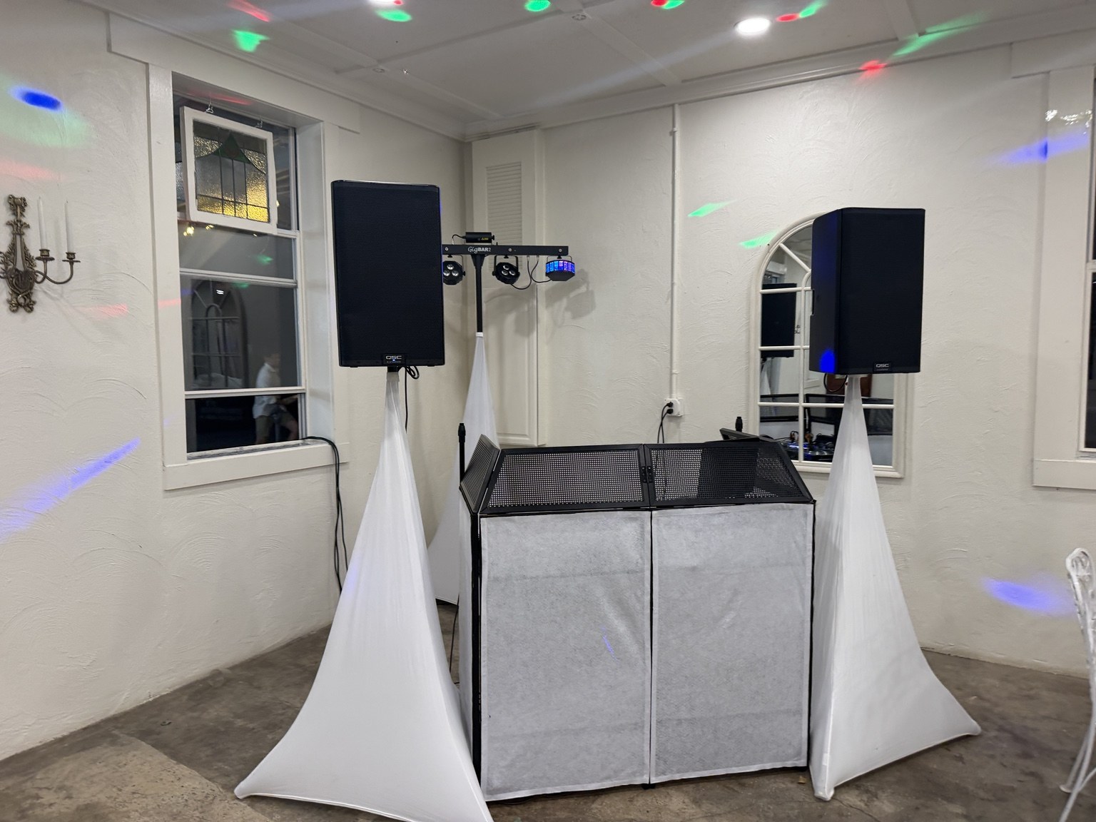 DJ setup with speakers, facade, lighting, and party lights in a venue room