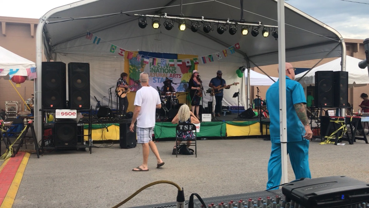 Outdoor festival stage with band, speakers, and lighting